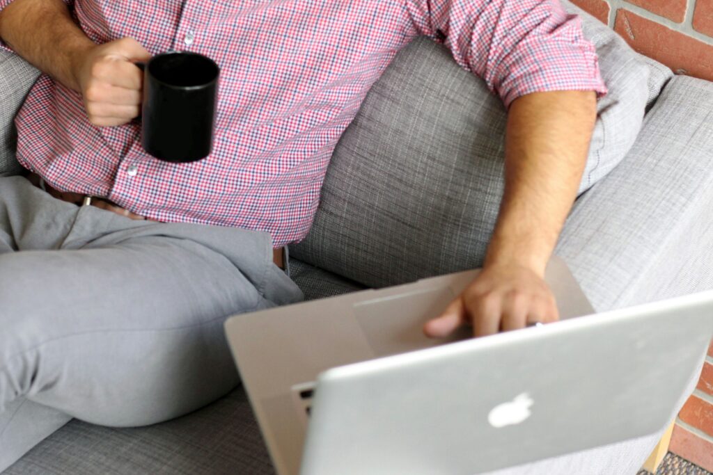 A man sitting on a couch using a laptop, checking if he qualifies for Social Security Disability Insurance (SSDI).