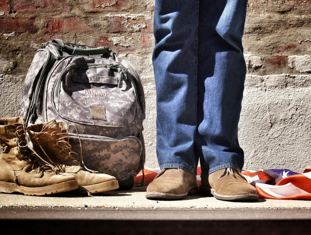 A soldier’s bag and boots beside their feet, symbolizing the backlog of VA disability claims.
