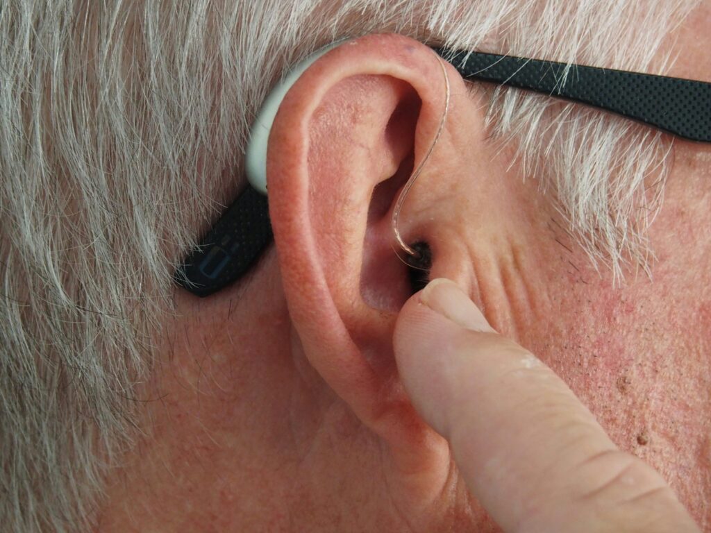 An elderly man holding his ear, highlighting hearing loss as one of the most common workplace injuries.