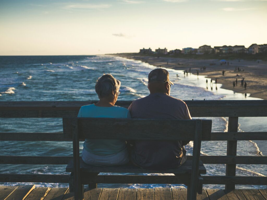 An elderly couple sitting on a beach, illustrating the impact of retirement on existing SSDI benefits.