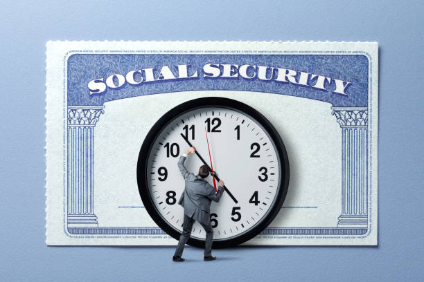 A man in a suit holds onto the hand of a clock which stands in front of a large Social Security card.