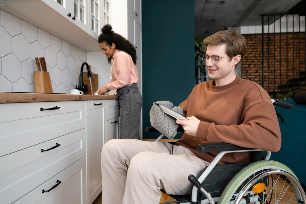 A man in a wheelchair happily drying a plate, representing potential tax breaks for persons with disabilities and their caregivers.