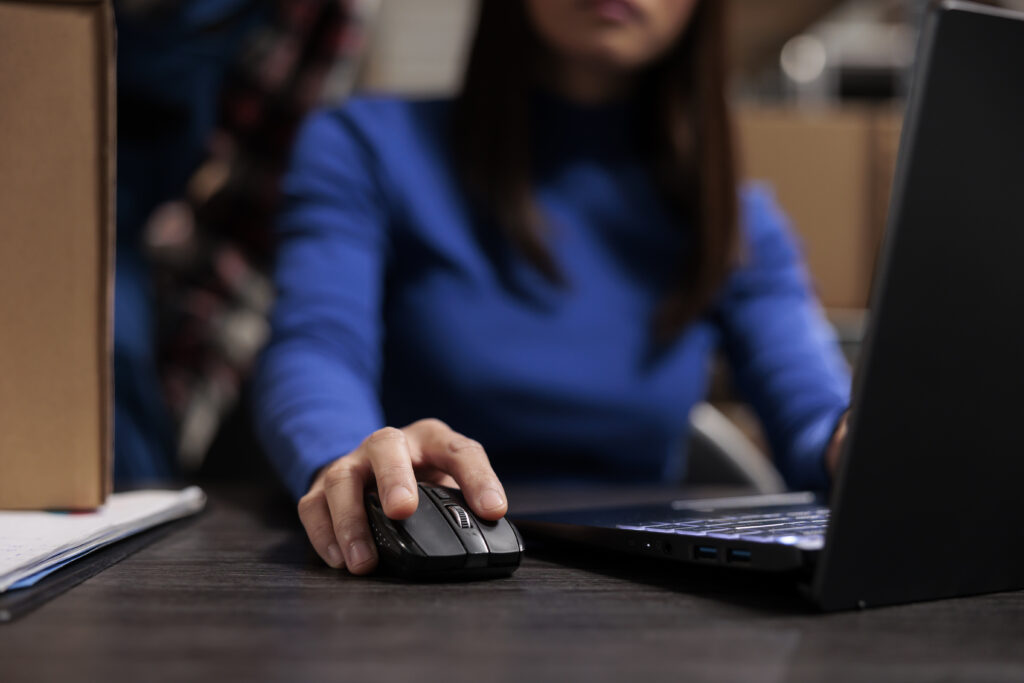 A woman using a laptop, researching issues related to fraud and Social Security benefits.