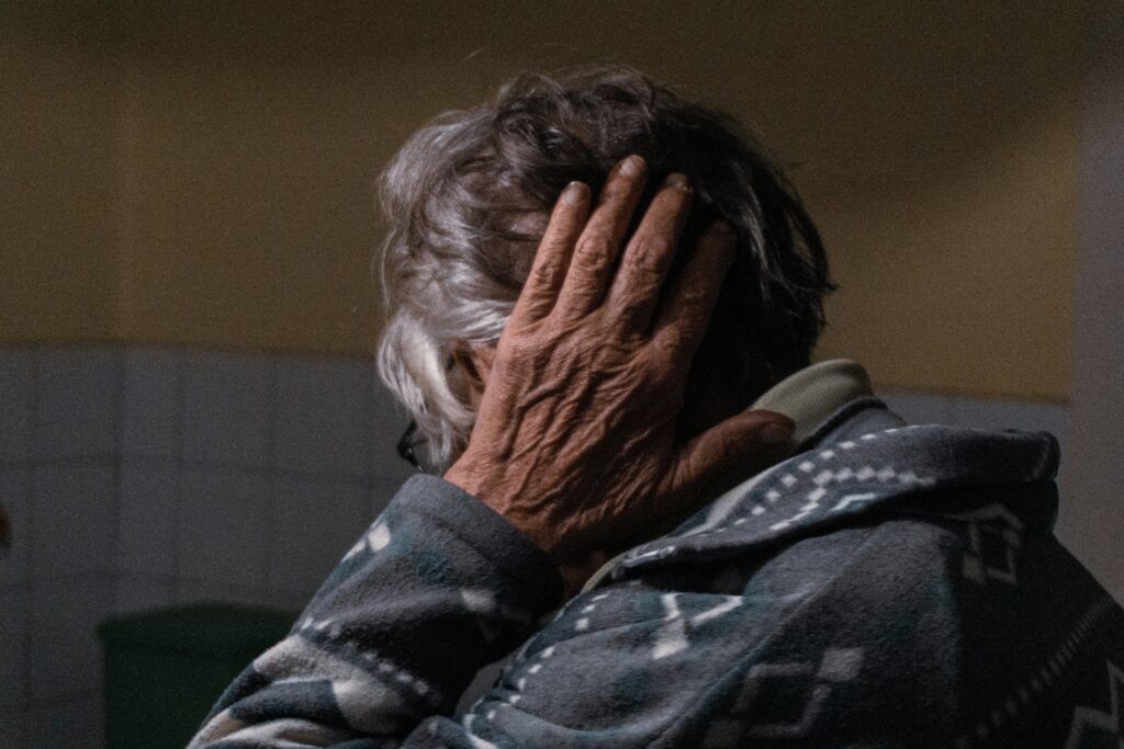 An elderly man covering his ears, representing the evaluation process for disabling impairments in California.