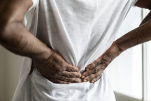 A person indicating back pain, representing musculoskeletal disorders that may qualify for Social Security Disability in California.
