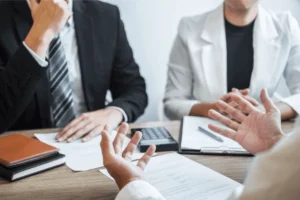 People seated at a table, examining papers and a laptop, engaged in a discussion about Social Security Disability claims. What to Do If Your Social Security Disability Claim Is Denied in Fresno, CA