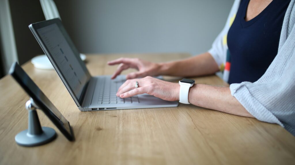 A woman using a laptop to research retroactive SSDI benefits and understand how far disability back pay can go in California.
